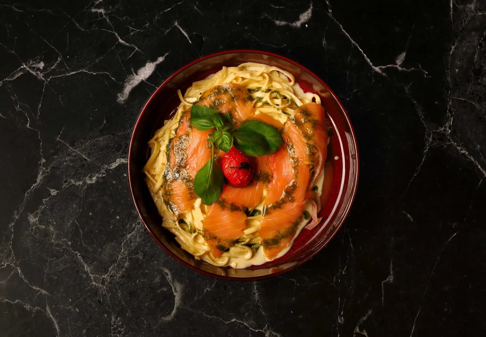 Tagliatelles au saumon fumé, pesto de basilic et tomate cerise rôtie sur marbre noir