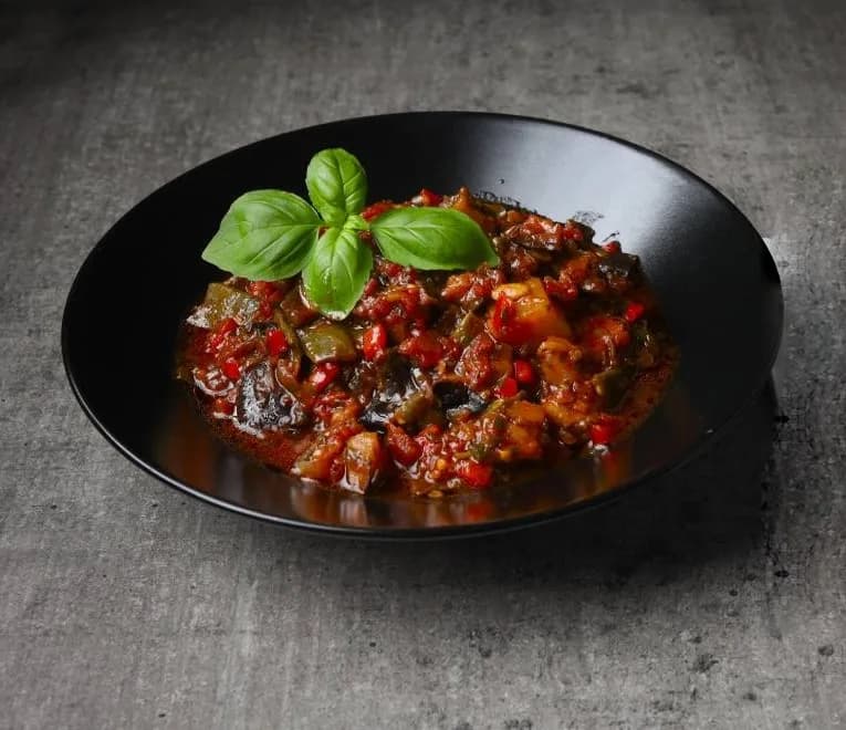 Ragoût de légumes mijoté au basilic dans une assiette noire